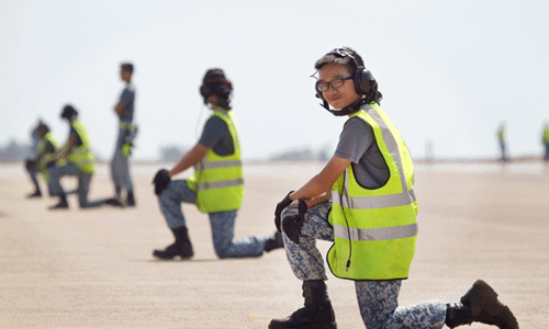 Trong ảnh là một nữ nhân viên ngồi xen kẽ trong đội hình nhân viên hướng dẫn bay mặt đất.