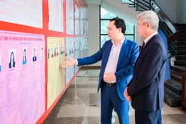 Ông Vũ Văn Tiến, Ủy viên Đoàn Chủ tịch, Trưởng Ban Tuyên giáo Cơ quan Ủy ban Trung ương MTTQ Việt Nam cùng cử tri xem thông tin người ứng cử