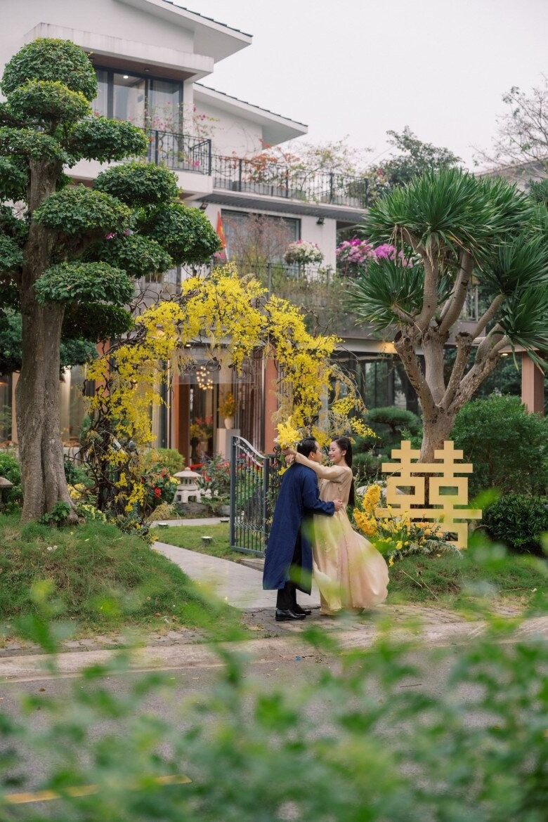 Trước cổng biệt thự được trang trí tông vàng ấm áp, hai bên là cây phát tài núi và tùng la hán. Ảnh: FBNV