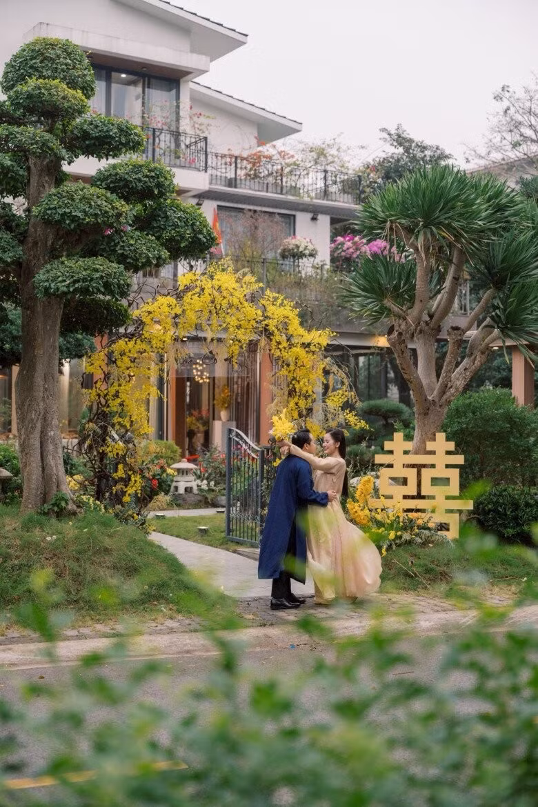 Trước cổng biệt thự được trang trí tông vàng ấm áp, hai bên là cây phát tài núi và tùng la hán. Ảnh: FBNV