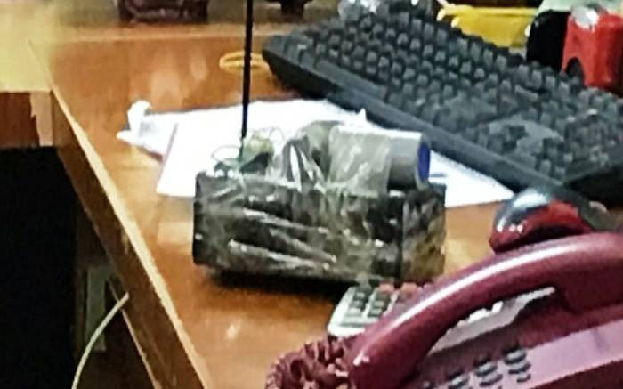 Quay lại với hiện trường vụ án, khi tiến hành khám nghiệm, công an thu giữ quả mìn tự chế mà đối tượng bỏ lại. Quả mìn này về sau được xác định là giả. Tên cướp đã rất ranh ma dùng vỏ hộp điện thoại Iphone rồi quấn băng dính màu đen để giả làm mìn đe dọa nhân viên ngân hàng. Chiếc vỏ hộp điện thoại này có nhiều dấu vân tay. (Mìn tự chế giả tên cướp để lại hiện trường)