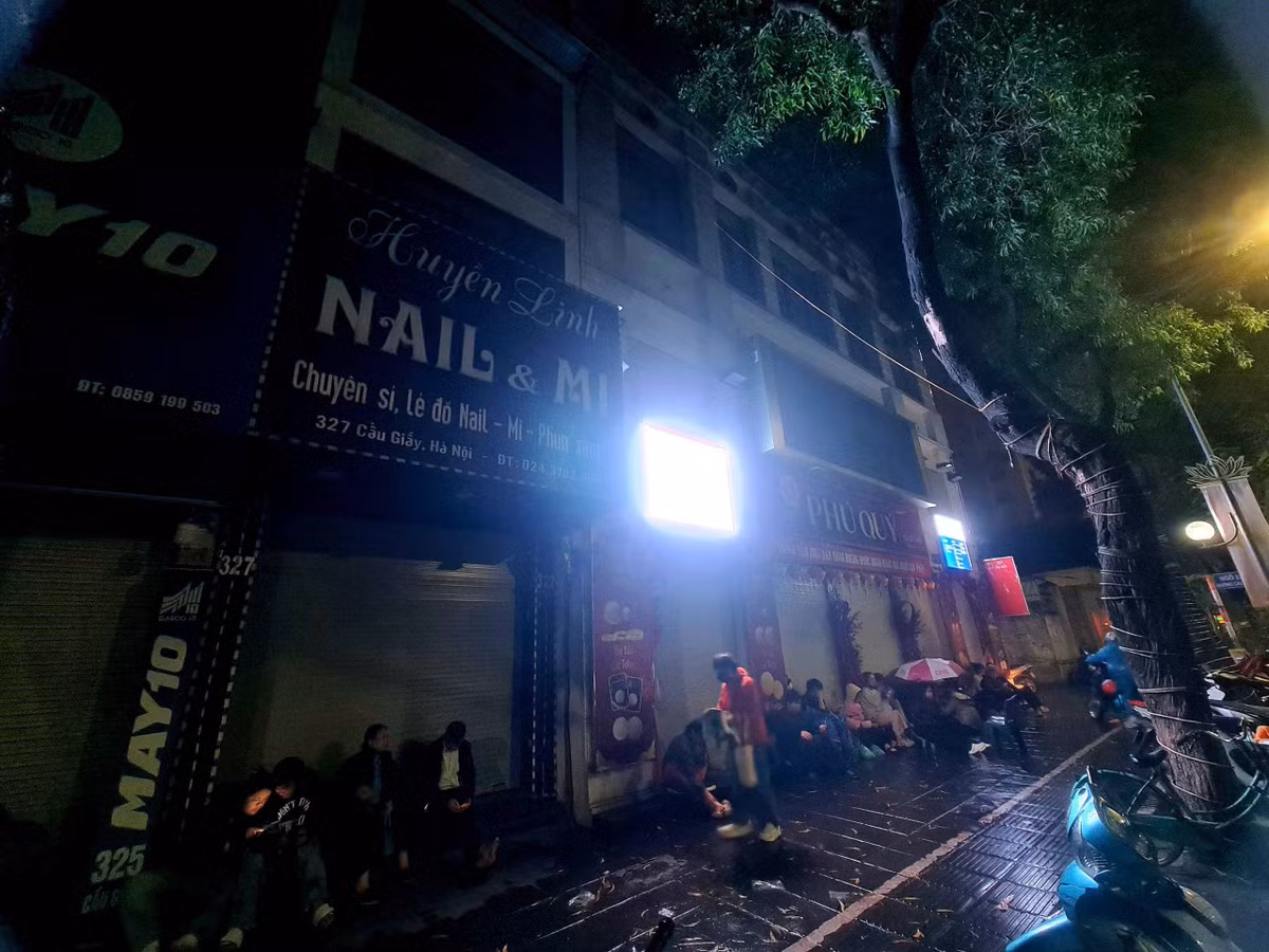 Người dân xếp hàng dài, nép vào dãy hiên tránh mưa, kiên nhẫn chờ cửa hàng vàng bạc Phú Quý trên đường Cầu Giấy, Hà Nội mở cửa để mua vàng. Ảnh: Mạnh Hưng.