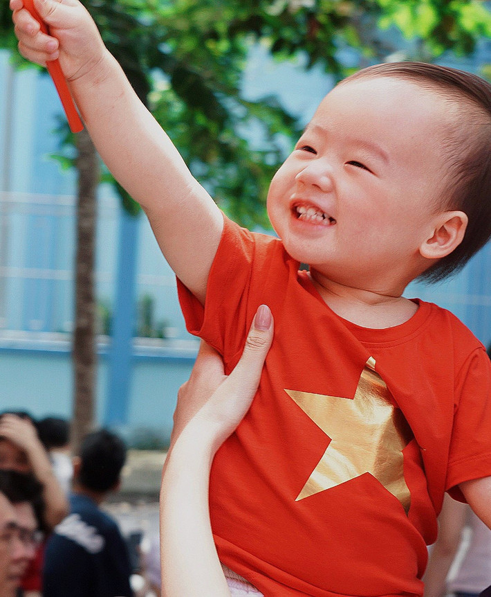 Bé Tino diện áo màu cờ đỏ sao vàng.