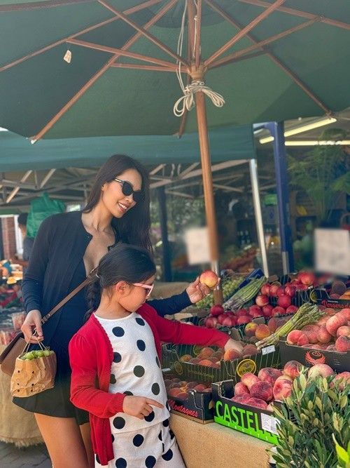 Nữ người mẫu đưa con gái đi chợ mua hoa quả tươi. Ảnh: FB Hà Anh.