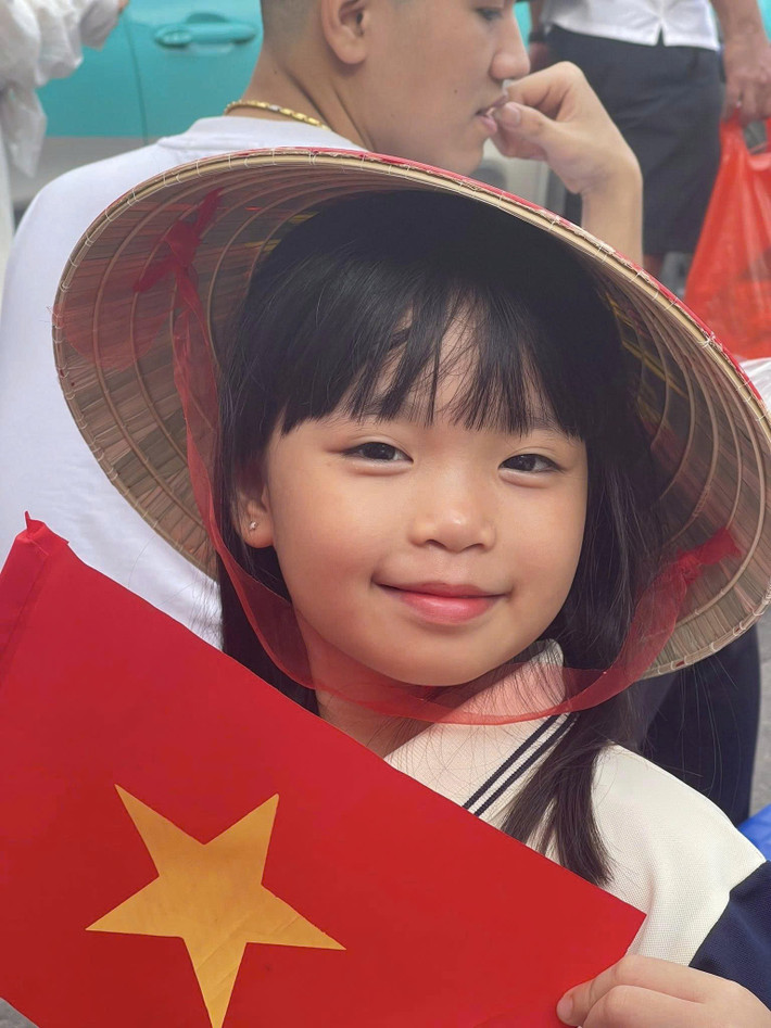 Bé gái hào hứng chờ đợi xem diễu binh, diễu hành.