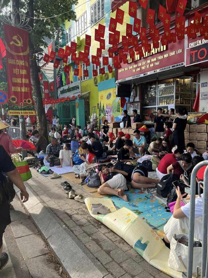 Từng nhóm gia đình, bạn trẻ, người lớn tuổi trải bạt, chiếu để chờ xem diễu binh, diễu hành 2/9.