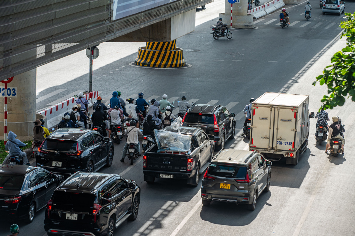Tại một ngã tư trên đường Hồ Tùng Mậu, người điều khiển xe máy chen chúc dừng đèn đỏ tại khu vực có bóng râm.