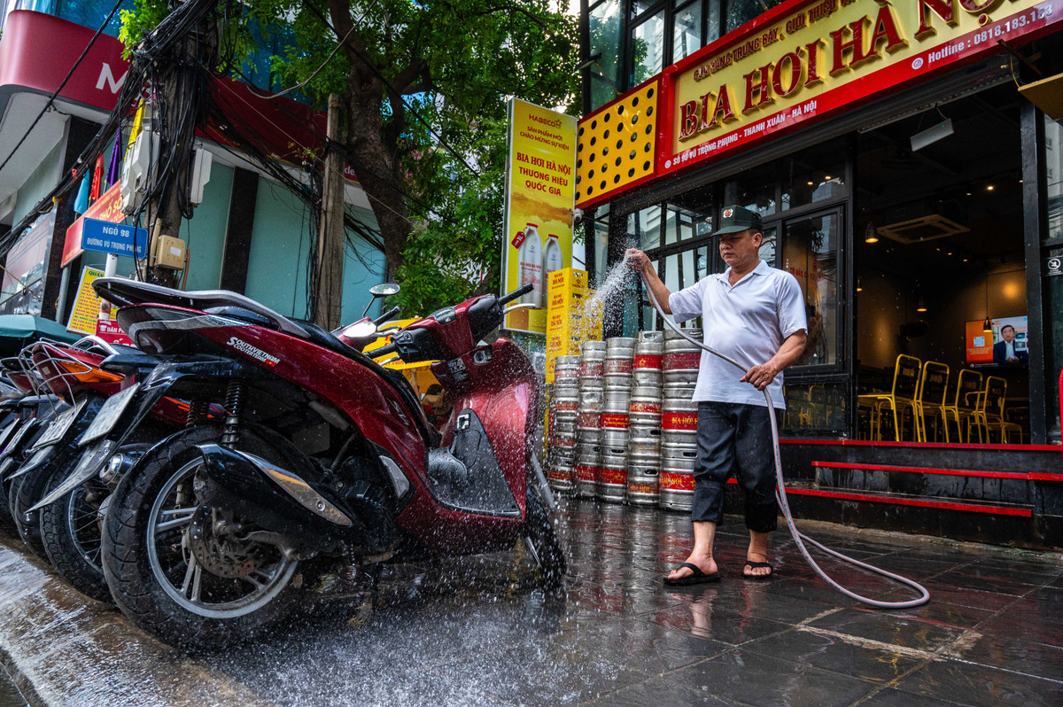 Một nhân viên tại nhà hàng trên đường Vũ Trọng Phụng xịt nước lên xe máy và vỉa hè để giảm nhiệt. Theo cơ quan khí tượng, trong ngày 3/8, Hà Nội là nơi nóng nhất trên cả nước, với nhiệt độ trong lều khí tượng khu vực nội thành gần 40 độ C. Dự báo, chiều tối và đêm 4/8, ở thủ đô có thể xảy ra mưa rào và dông vài nơi. Gió nhẹ. Trong mưa dông có khả năng xảy ra lốc, sét và gió giật mạnh.