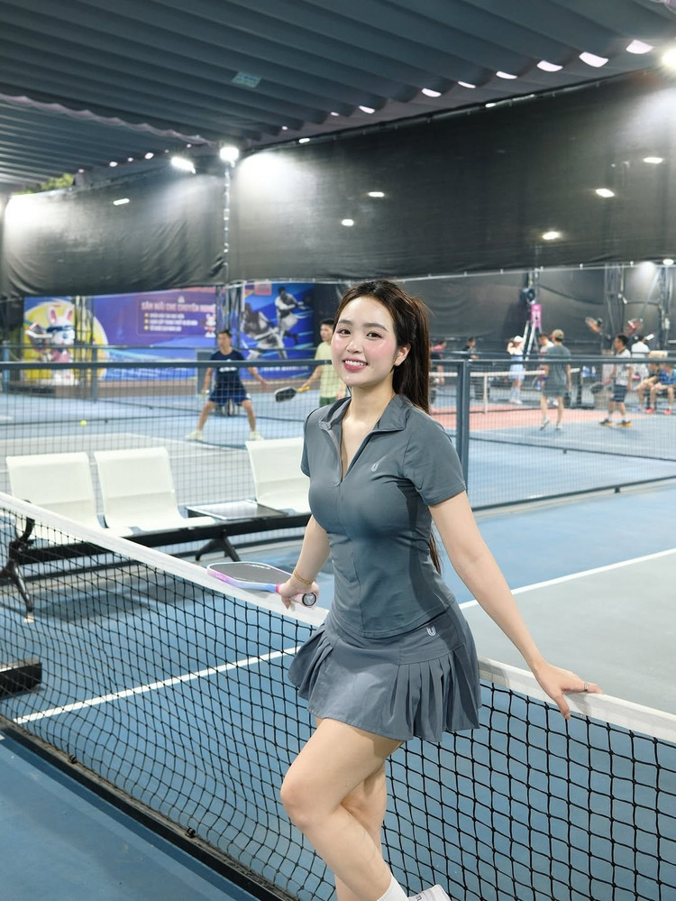 Điểm nhấn của trang phục là chiếc áo polo có khóa kéo cổ V, mang lại vẻ trẻ trung và hiện đại. Cô nàng kết hợp với đôi giày thể thao trắng cùng tất cao cổ, tạo nên một tổng thể hài hòa và đúng chất dân thể thao. hot-girl-ha-thanh-choi-pickleball-6.jpg