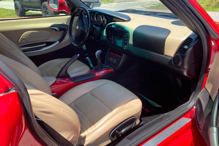 Tổng quan nội thất của chiếc Porsche Boxster này vẫn được giữ nguyên với tông màu nâu/đen. Khu vực tựa tay trung tâm cũng được sơn lại màu đỏ giống ngoại thất.