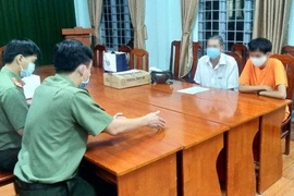 P.T. (áo cam) tại cơ quan công an.