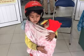 Xôn xao hình ảnh bé gái 7 tuổi bế em đi tiêm phòng