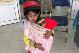 Xôn xao hình ảnh bé gái 7 tuổi bế em đi tiêm phòng