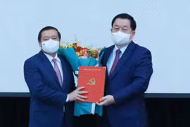 Ông Nguyễn Trọng Nghĩa trao quyết định và tặng hoa chúc mừng ông Lại Xuân Môn. 