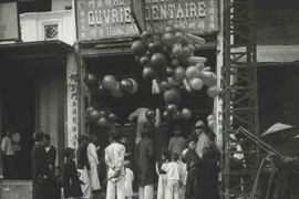 Trẻ em và người lớn bị thu hút bởi những trái bóng bay tại một cửa hàng ngày Tết.