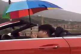 Thanh niên lái xe mui trần cầm ô che mưa