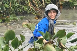 Nữ sinh cười rạng rỡ, ngâm mình dọn rác dưới đầm nước