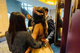 Bạn thân cô dâu nắm tay chú rể sau lưng khi cùng chụp ảnh