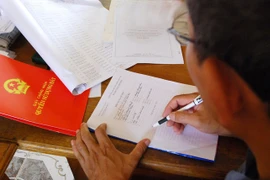 Nhân viên của Văn phòng đăng ký đất đai nhận tiền để ra nhanh sổ đỏ