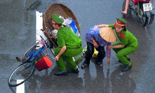 Hai chiến sĩ công an trẻ tuổi bất chấp trời mưa, ướt áo dừng lại giúp đỡ một cụ già đi đường chẳng may đổ chiếc xe đạp cùng với vật dụng mưu sinh.