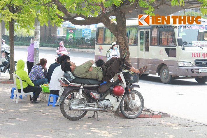 Một bác xe ôm tranh thủ nằm nghỉ dưới gốc cây