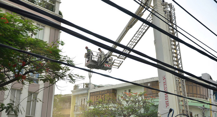 Một tổ chiến sĩ khác dùng xe thang tiếp cận sân thượng di chuyển khoảng chục người đang mắc kẹt đưa xuống đất.