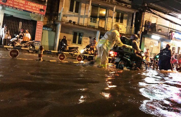 Người dân bì bõm lội qua rốn ngập trên đường Tô Ngọc Vân, quận Thủ Đức.