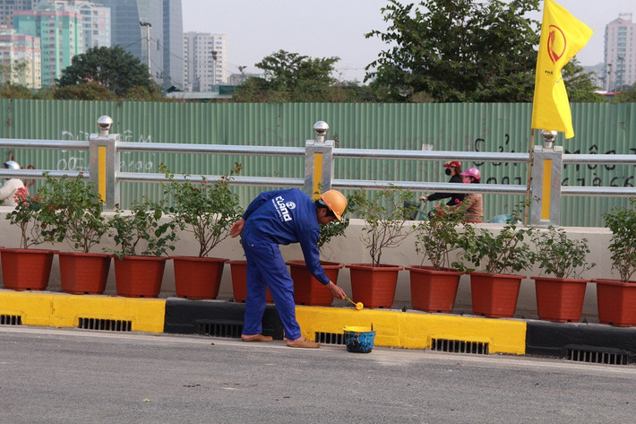 Công nhân đang gấp rút hoàn thành công việc sơn tại dải phân cách.