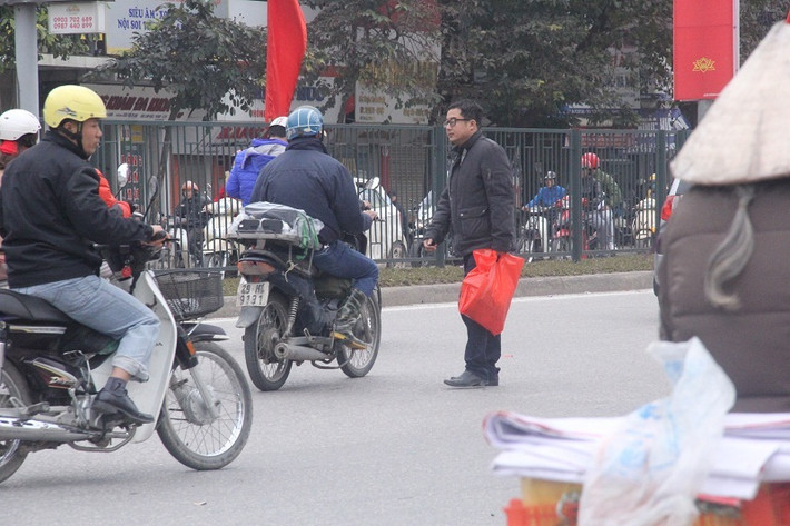 Một người dân vừa đi vừa lách qua các đầu xe để sang đường.