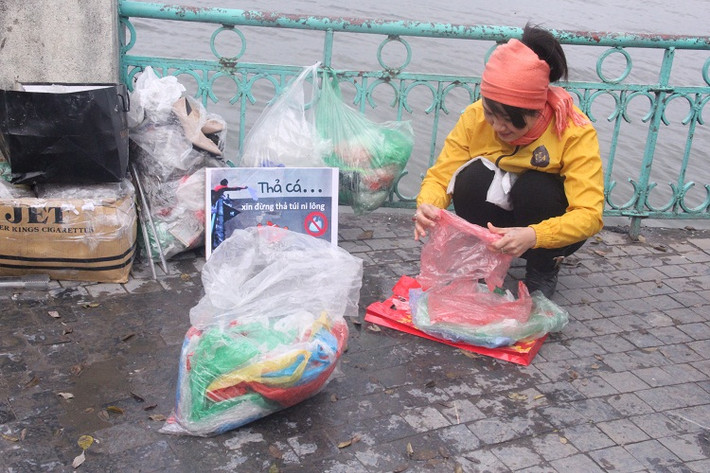 Tình nguyện viên mang thông điệp “Thả cá xin đừng thả túi nilon” kiên định “bám chốt” kêu gọi mọi không vứt túi nilon xuống hồ.