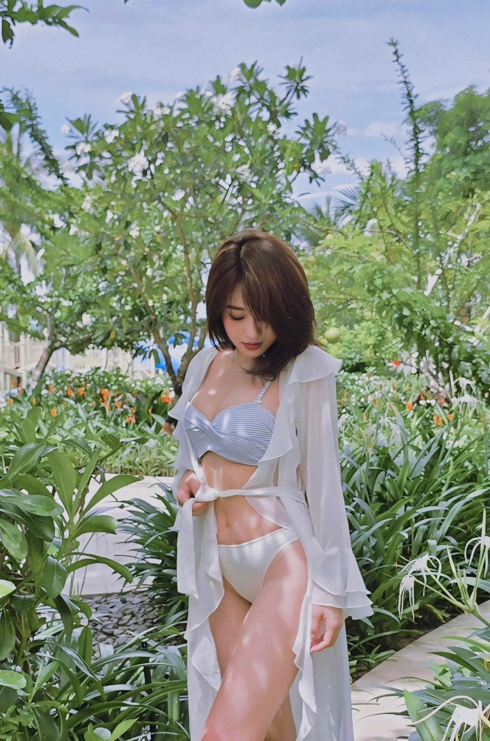 Trong clip, Hà Kim xuất hiện với bikini trắng gợi cảm, khoác ngoài chiếc áo mỏng nhẹ, bước đi tự tin giữa khung cảnh rợp nắng.