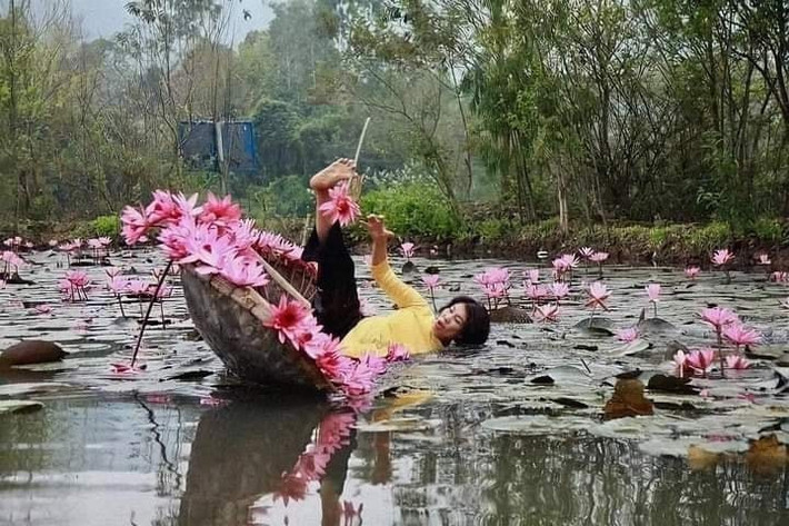Vị khách nữ uống nước khi ngồi trên thuyền tạo dáng khi chụp ảnh.