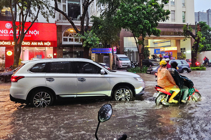 Nước ngập sâu khiến nhiều phương tiện giao thông bị chết máy, người dân phải bì bõm lội nước để di chuyển.