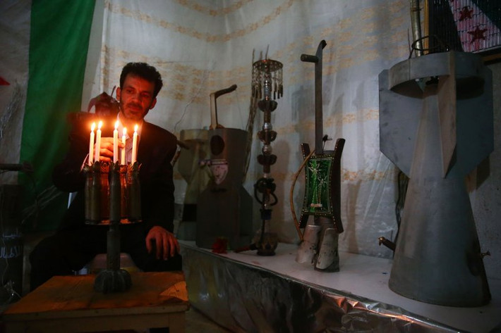 Một người đàn ông Syria đang thắp những cây nến với chân nến được làm từ những món vũ khí chiến tranh.