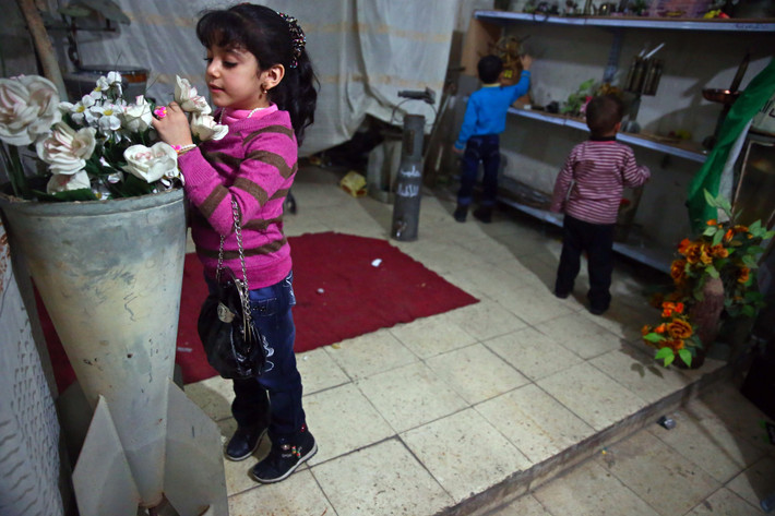 Một bé gái Syria say mê ngắm những bông hoa được cắm trong chiếc bình khổng lồ được chế từ vỏ tên lửa.
