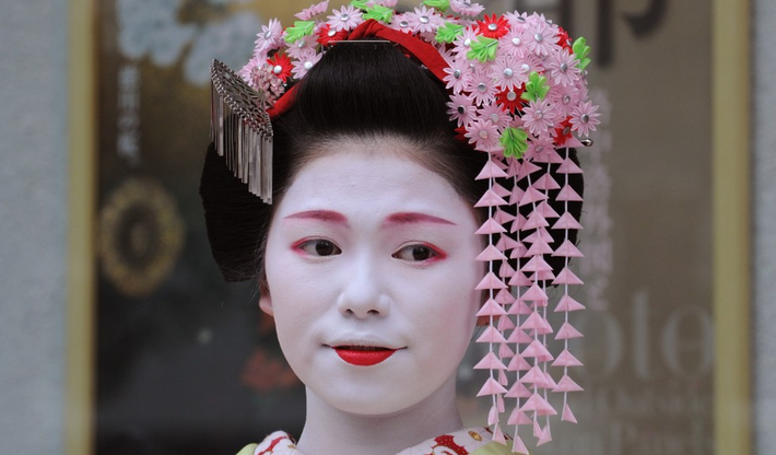 Cổ áo đỏ ở kiểu áo kimono dài tay này chỉ ra rằng Toshitomo là một geisha thực tập.
