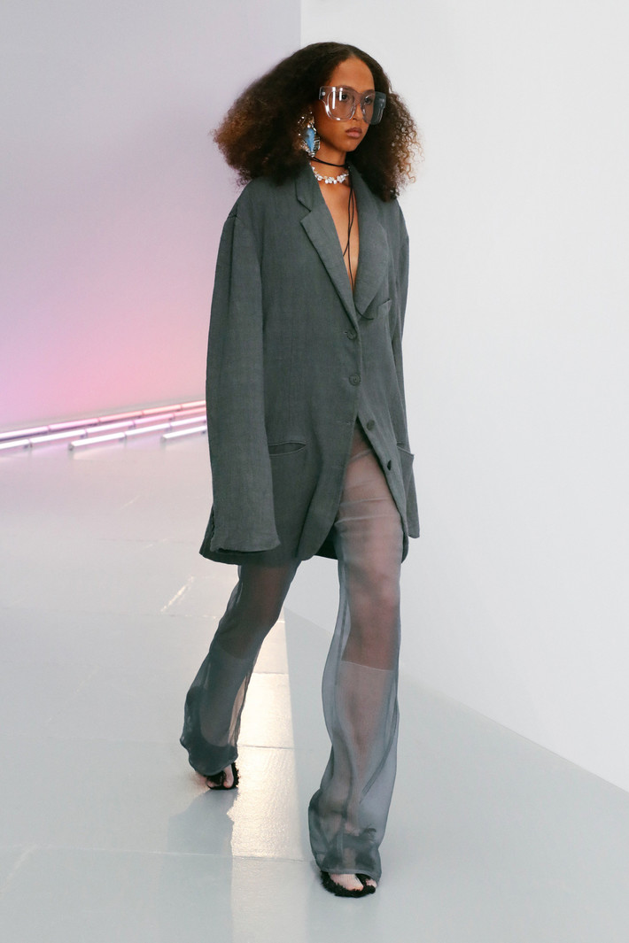 Acne Studios trông sành điệu hơn khi hòa quyện chất liệu vải sheer cùng phom dáng quần ống suông đi kèm blazer quá khổ đậm tinh thần menswear. Sự pha trộn giữa tông màu xám đậm và nhạt hay chất liệu vải khác nhau là điểm nhấn cho xu hướng ăn mặc gợi cảm năm 2021. Ảnh: Vogue.