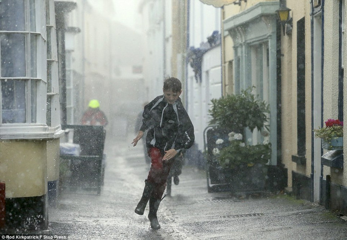 Một cậu bé ở Appledore, North Devon đội đầu trần chạy trong cơn mưa lớn tránh bão.