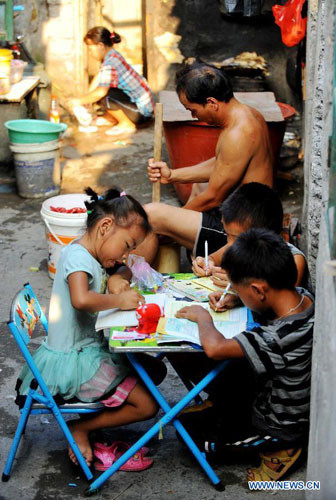 Bé gái Pan Simei, 7 tuổi và 2 bạn học ở làng Baisha thành phố Liuzhou, chung nhau một chiếc bàn nhỏ. 2 bé trai thậm chí còn không có ghế ngồi.