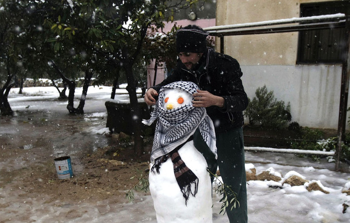 Một thanh niên Palestine thích thú nặn ông già tuyết ở thành phố Bờ Tây Nablus ngày 13/12. Năm nay, người Israel and Palestine chịu nhiều cơn bão tuyết dữ dội sớm hơn khiến nhiều người ngạc nhiên, lo lắng.