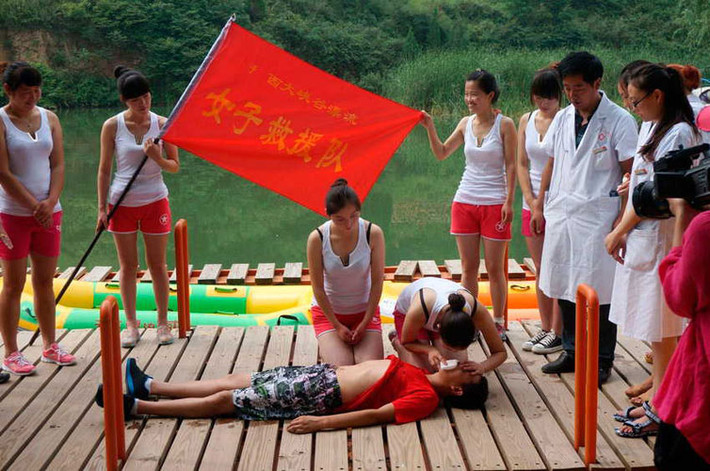 Các cô gái tập trung thành vòng tròn, lần lượt thực hành hô hấp nhân tạo trên người thật.