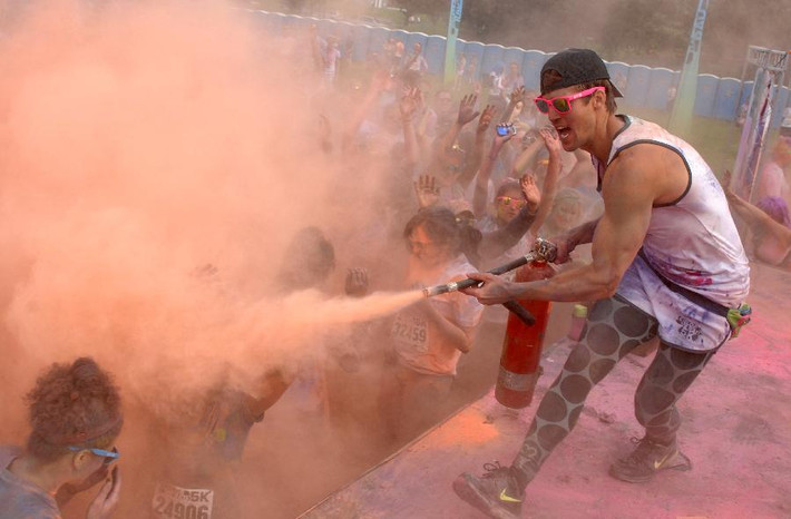 Một nam thanh niên phấn khích phun bột màu vào đám đông tham dự cuộc thi chạy ném bột màu Colour Me Rad 5K 2013.