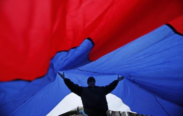 Một người biểu tình ủng hộ Nga giơ 2 tay nâng cao lá cờ Nga khổng lồ ngày 27/2 tại Simferopol.