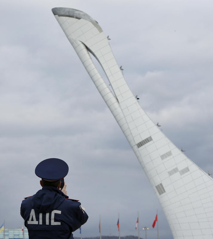 Một nhân viên an ninh đứng trước ngọn đuốc Olympic tại công viên Olympic ở Sochi.