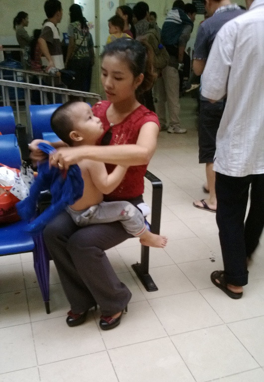 Vì quá đông nên cháu bé này phải ra ngoài mặc áo sau khi khám, để nhường chỗ cho bệnh nhân khác.