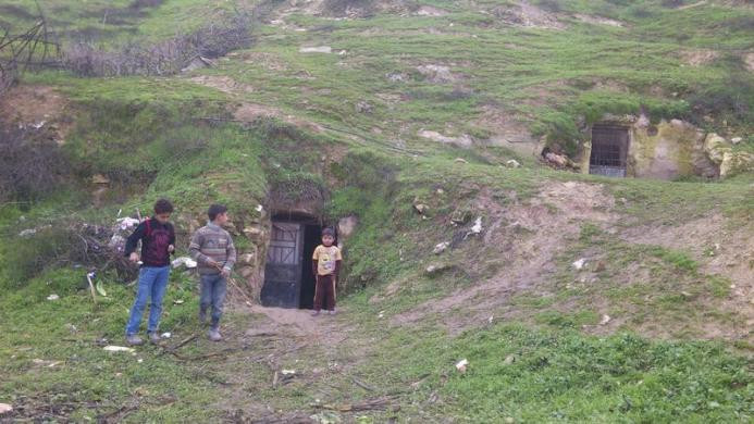 Ba cậu bé Syria chơi bên ngoài một hang động trong lòng đất - "ngôi nhà mới" tránh mưa bom bão đạn của chúng.