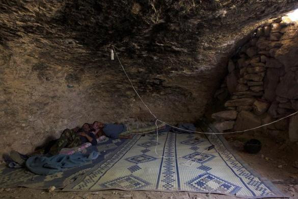 Một số chiến binh Syria nằm ngủ trên chiếc chiếu trải xuống nền đất trong hang động.