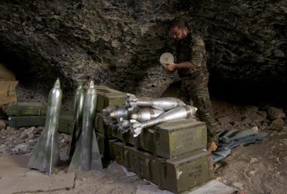 Một phiến quân Syria đang kiểm tra đạn dược, vũ khí trong hang động.