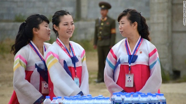 Các hướng dẫn viên của một hãng du lịch ở địa phương đứng trước bàn tiếp nước cho các tay đua trong cuộc đua xe đạp quốc tế.