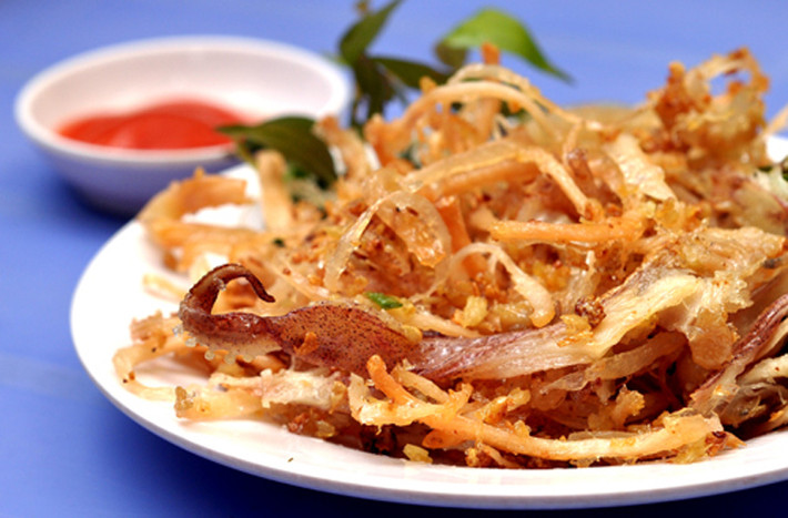 Khô mực chiên bơ. Không mang lại cảm giác dai khó cưỡng như khô mực nướng nhưng khô mực chiên bơ lại “đốn tim” người ăn bằng vị giòn rụm, cay cay vị tương ớt. Khô mực chiên bơ sẽ khiến anh ấy ăn mãi không chán, bất chấp cảm giác nóng hầm hập ngày hè.